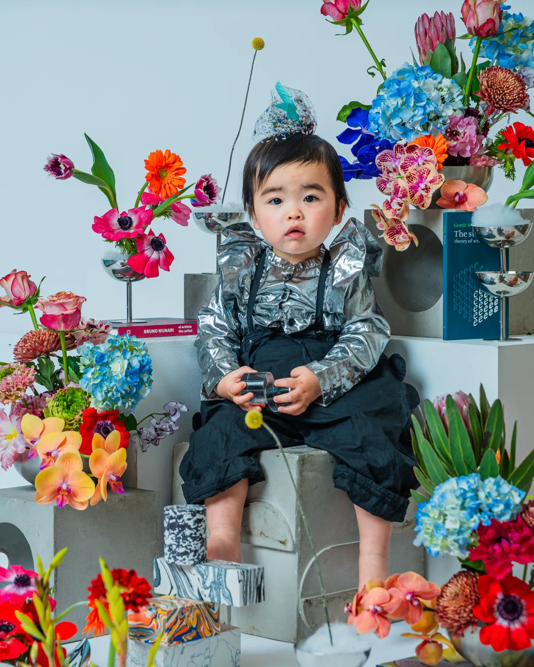 色とりどりの花に囲まれて座る幼児(KIDS & BABY)
