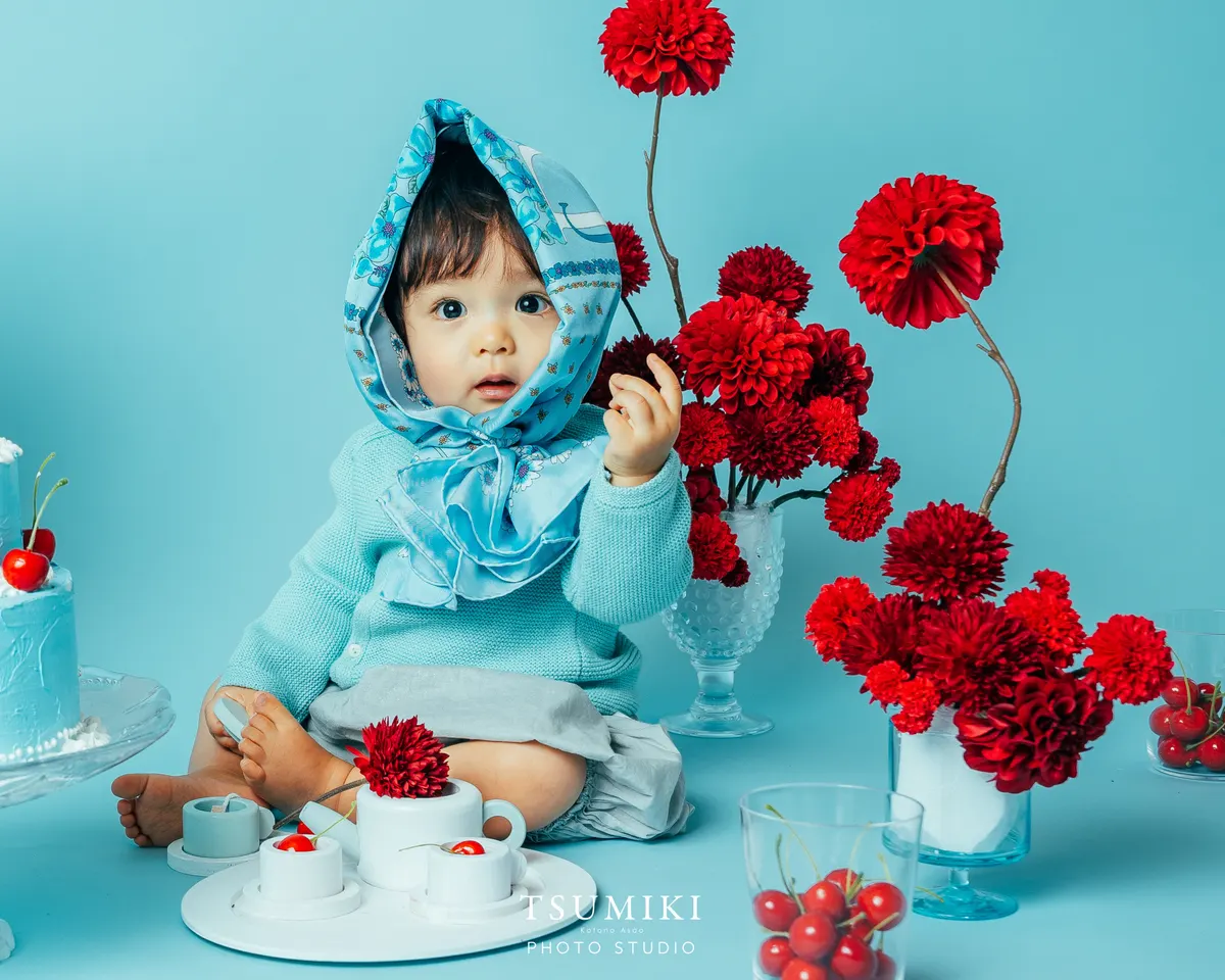 水色のスカーフを巻き赤い花を手にする赤ちゃん(Cherry シーン)