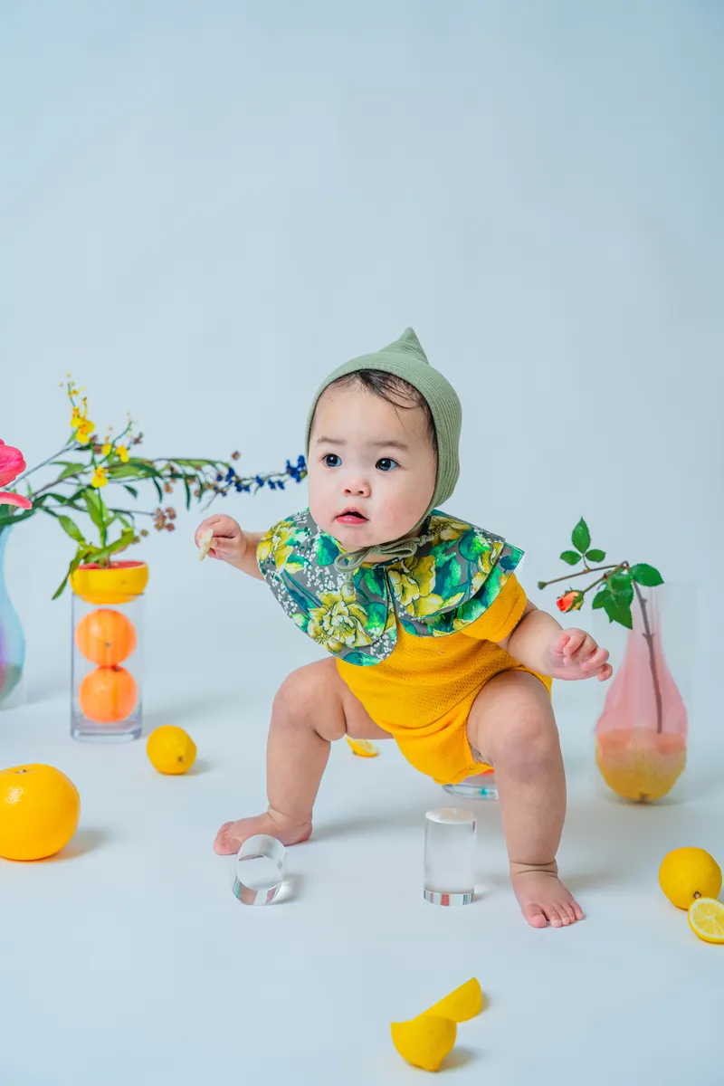 果物と花を背景に黄色い衣装で過ごす赤ちゃん(Fruit シーン)