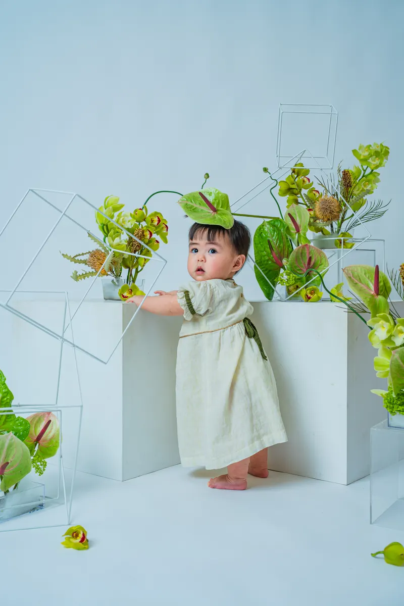 緑のアンスリウムと蘭に囲まれて立つ赤ちゃん(Garden シーン)