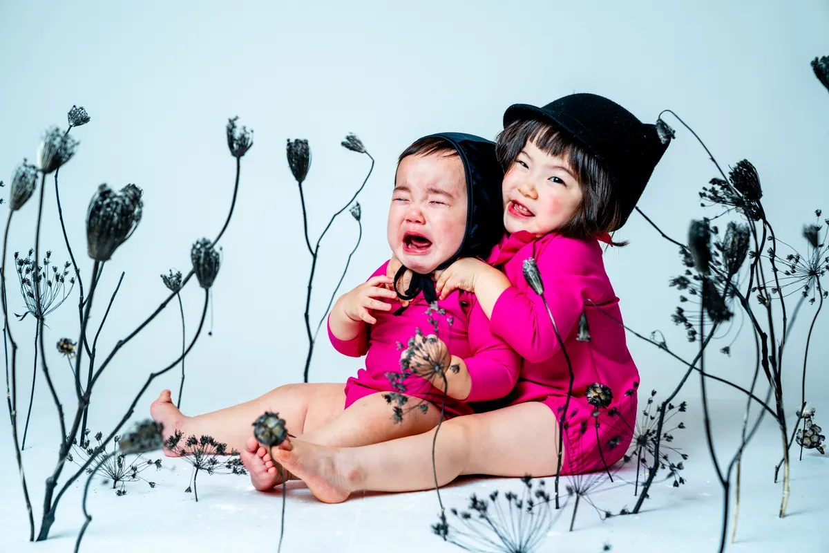 黒い枝花に囲まれて静かに写る子ども(Sumikuro シーン)