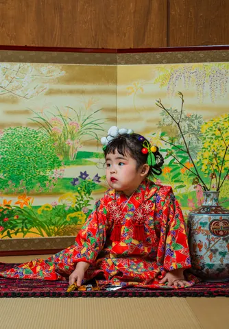 草花の屏風を背景に赤い着物で座る七五三の女の子（Byobu シーン）