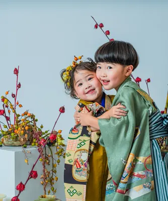 花飾りを前に抱き合って笑う着物姿の七五三の姉弟（kyoudai シーン）