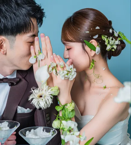 白い花を添えた手を顔の前で重ねる新郎新婦(Hands with flowers シーン)