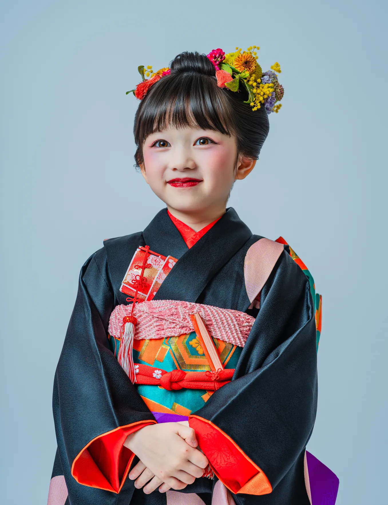 黒い着物で手を前に組み微笑む七五三の女の子