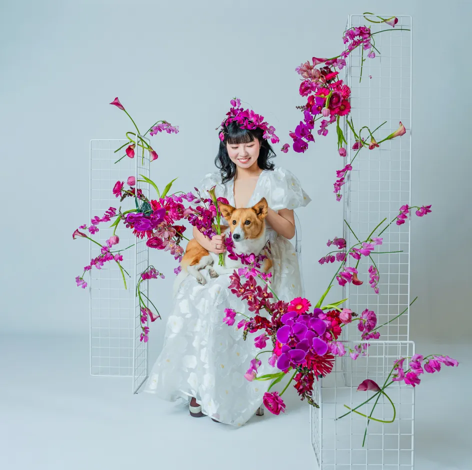 白いドレス姿でコーギー犬を抱きピンクの花に囲まれた花嫁