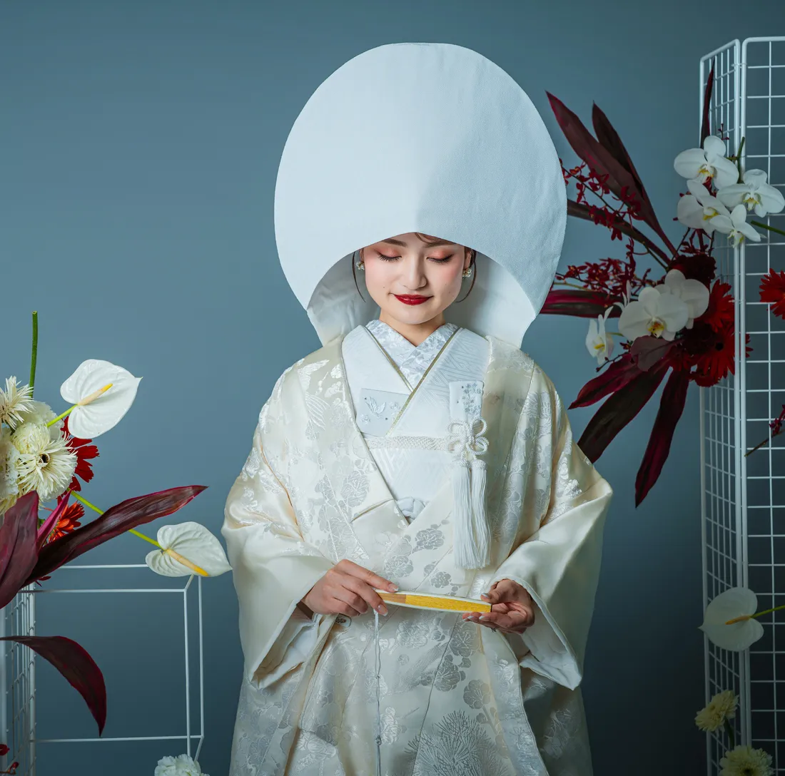 白無垢と綿帽子をまとい扇子を持ってうつむく和装の花嫁